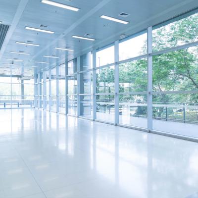 A view from inside a modern commercial space with floor to ceiling glass, trees visible outside.